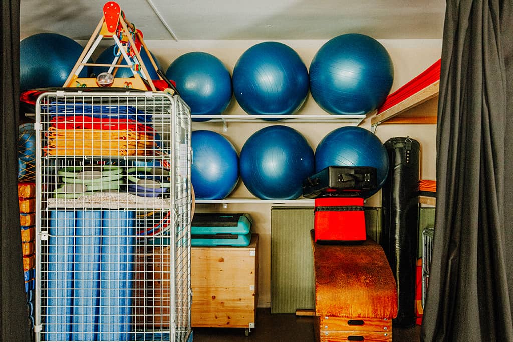 Blick auf Sportgeräte-Lager im KuBuS Jena: blaue Pezzibälle, Sportmatten und viele andere Geräte