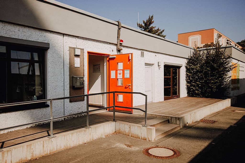 Blick auf die offenstehende orange Eingangstür des KuBuS Jena