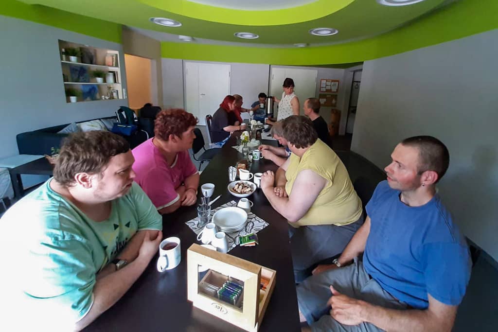 Blick auf die fröhliche Teilnehmerrunde beim Kaffeetrinken und Erzählen